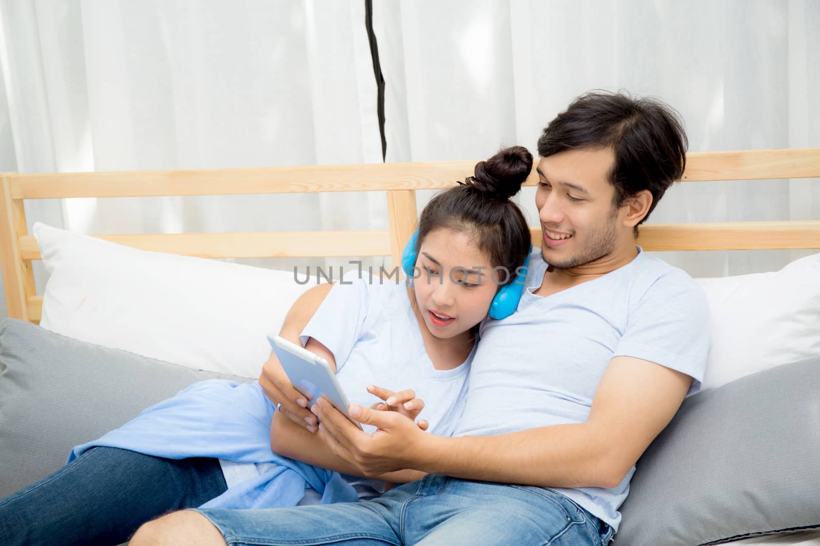 Beautiful asian young couple listening to music with tablet on bed, Love, dating,Young couple in sitting together in bed using a Tablet.