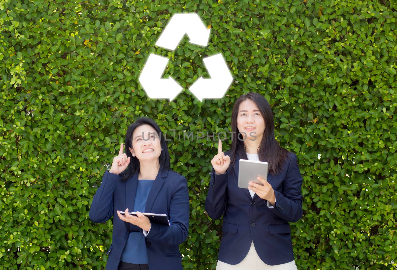 Asian woman two people pointing recycle symbol on nature background.
