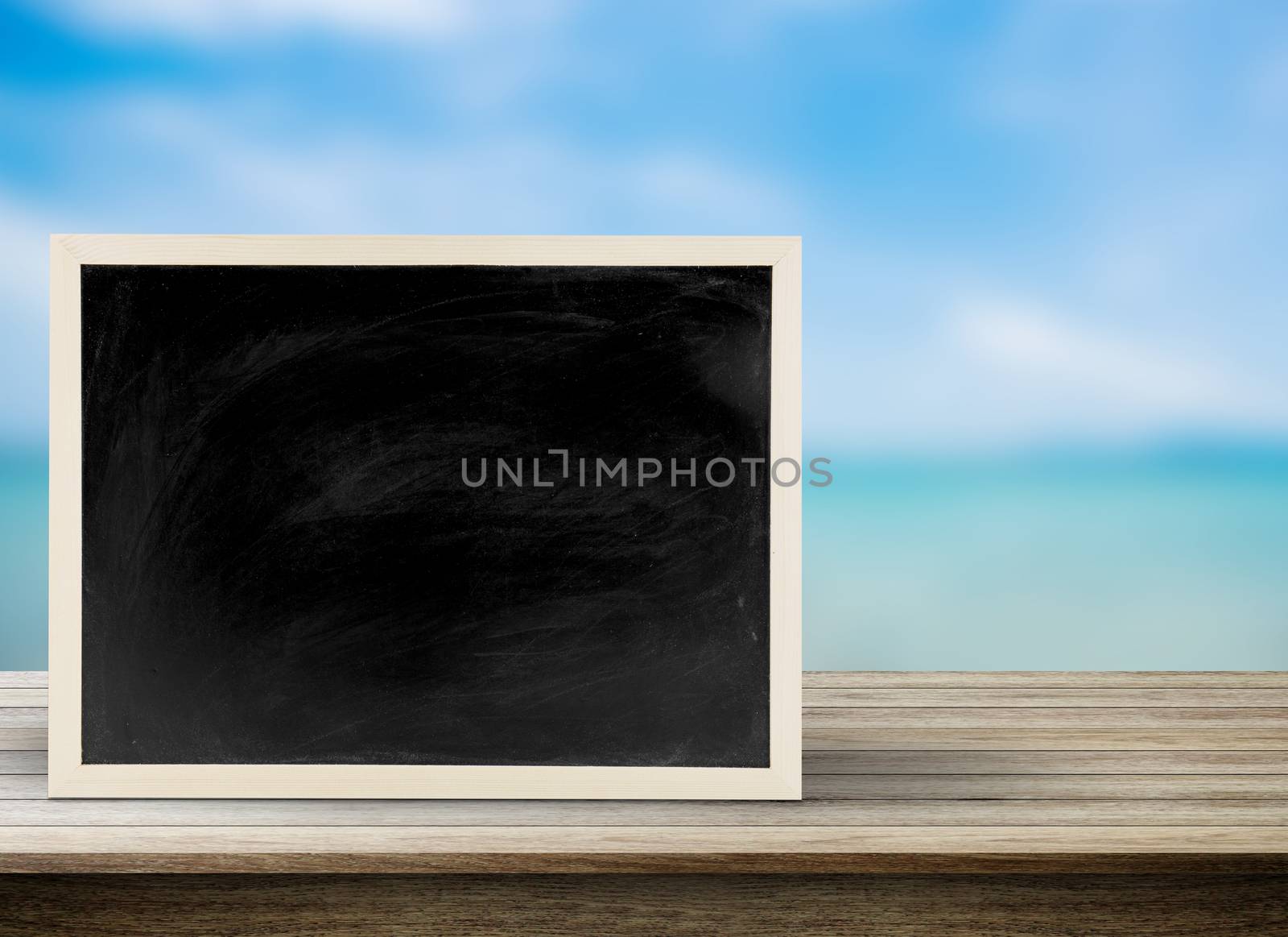 Blank chalkboard, blackboard on table with beach background with copy space, Blackboard on table for graphic apply work about business - can be used for display your products.