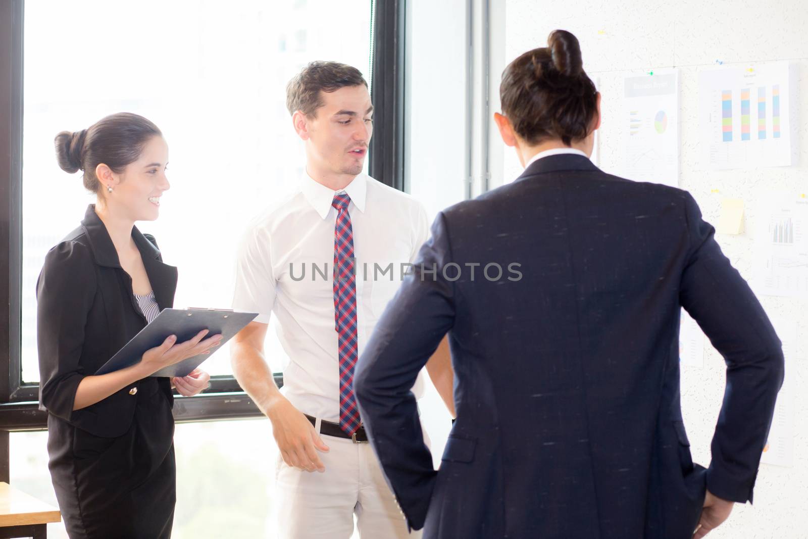 young businesspeople pointing towards graph with present profit while giving presentation in office, teamwork concept.