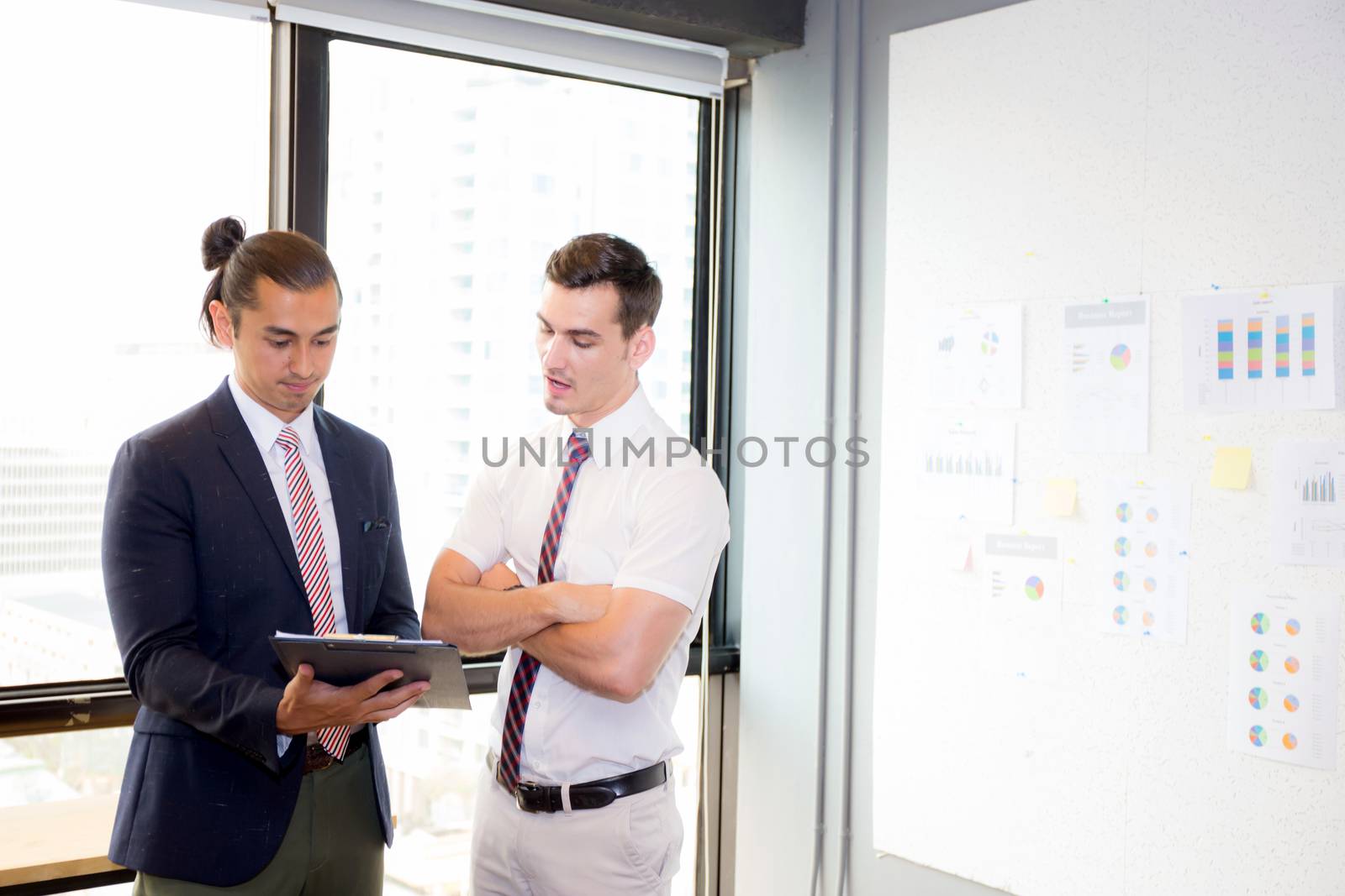 Asian young businessman two people holding clipboard and discussing work in the meeting room, business concept.