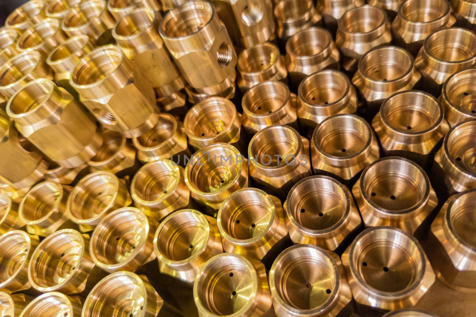 an abstract perspective industrial close-up background of shiny brass metal threaded hexagonal fitting parts.