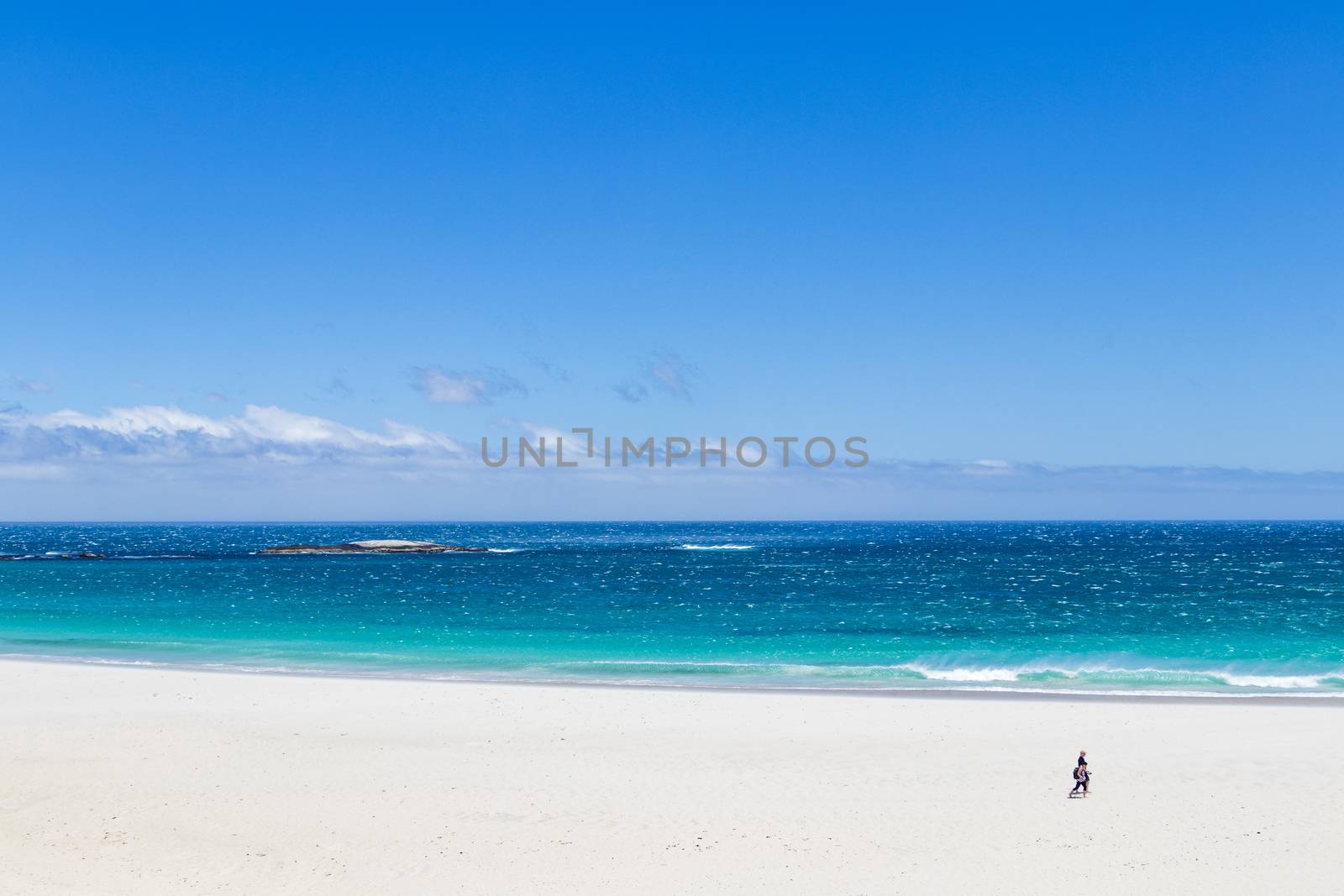 Camps Bay Beach in Cape Town, South Africa. Walking tourists on white sand.