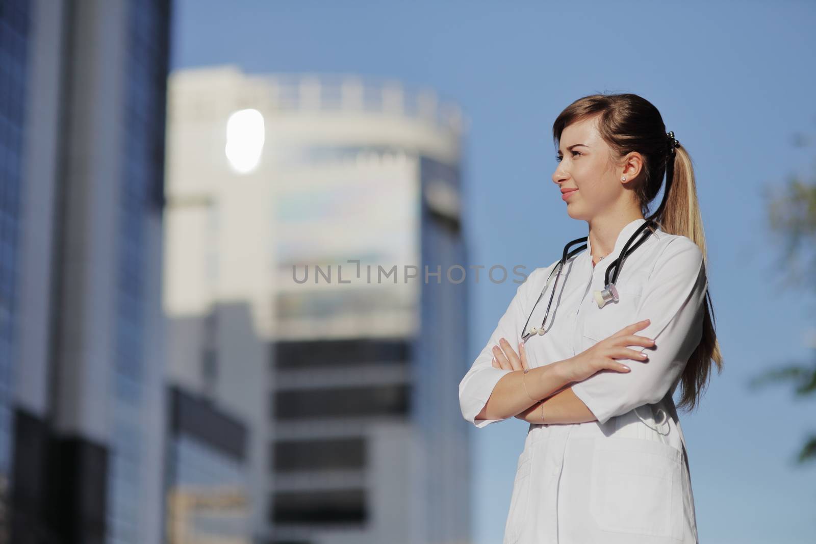 Portrait of a beautiful female doctor or nurse. Skyscraper, sky. Health concept. by selinsmo