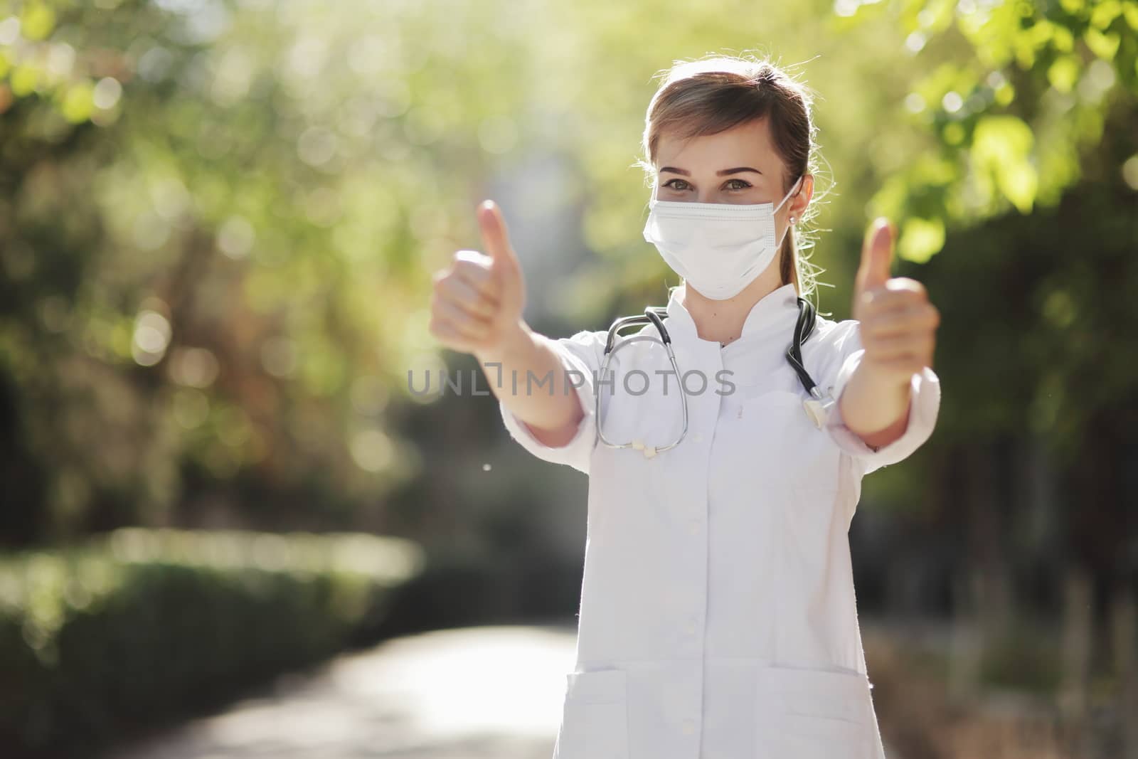 A female doctor or nurse in a protective face mask shows the class with her hand. Safety measures against the coronavirus. Prevention Covid-19 healthcare concept. Stethoscope. Woman, girl.