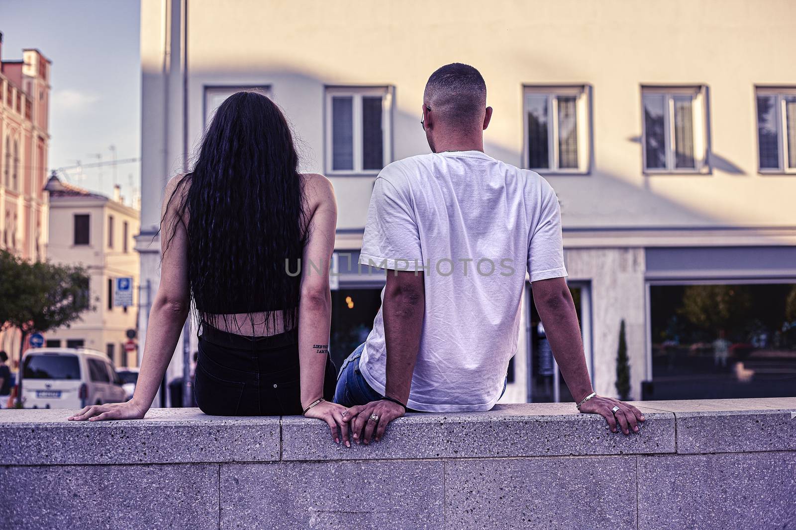 Young Love Couple sitting on a low wall in the city