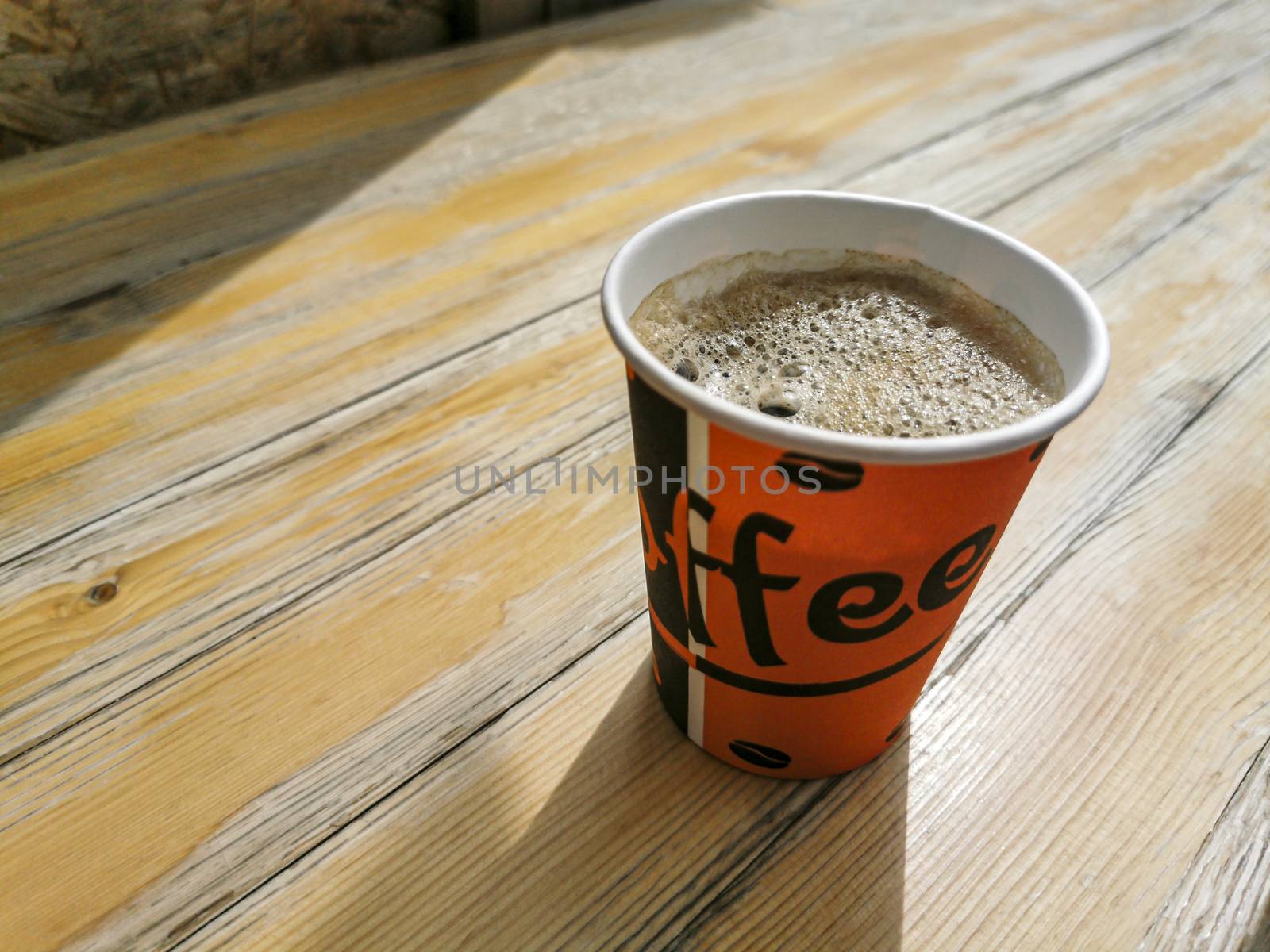 Red paper cup with coffee to go on wooden ground. Leherheide, Bremerhaven.