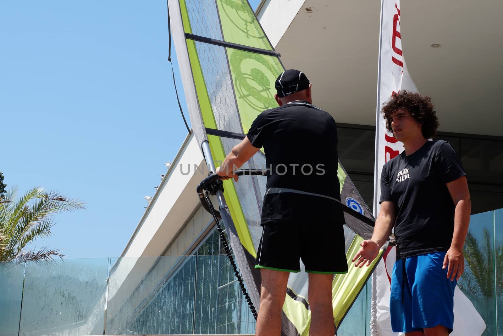 two men learning to windsurf at sea by Annado