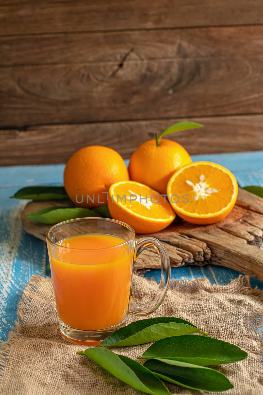 Fresh orange and a glass of orange juice on a wooden table background.