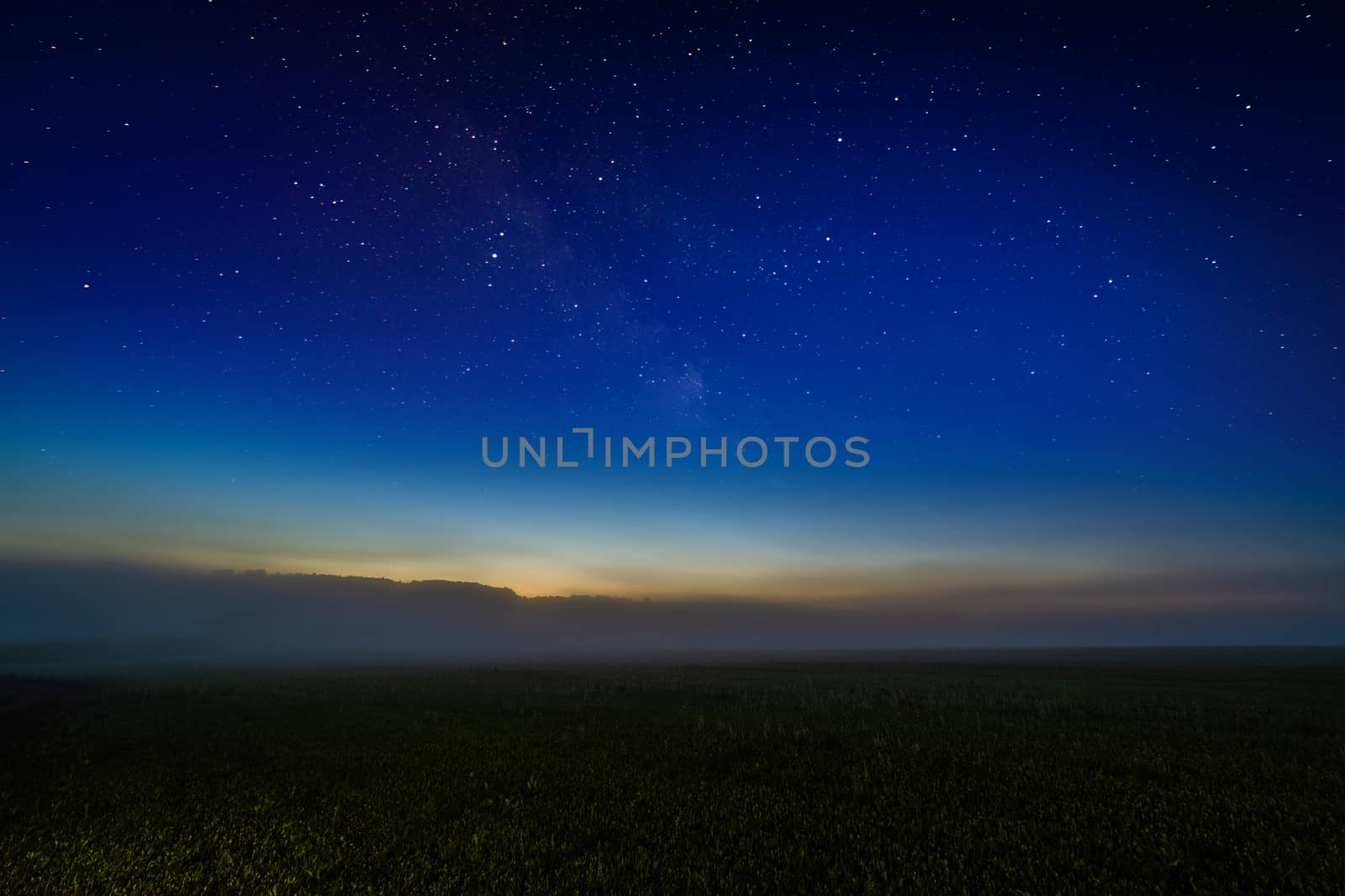 Foggy night field with starry night sky and afterglow horizon gradient. Collage.