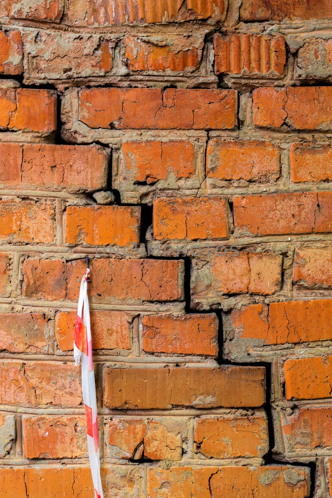 Deep cracked orange brick wall closeup texture and background. Vertical shot.
