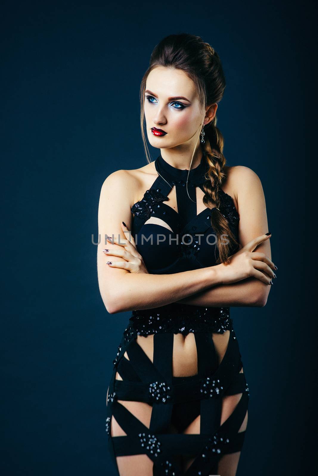 white girl model on a dark background in a dress made of cut stripes of black fabric