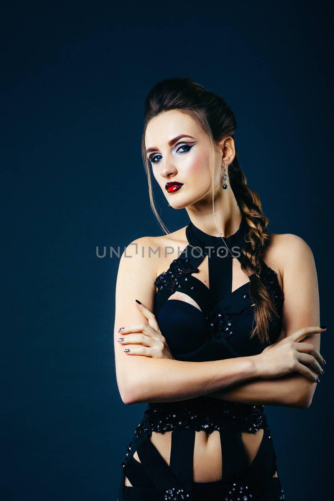 white girl modell on a dark background in a dress made of cut stripes of black fabric