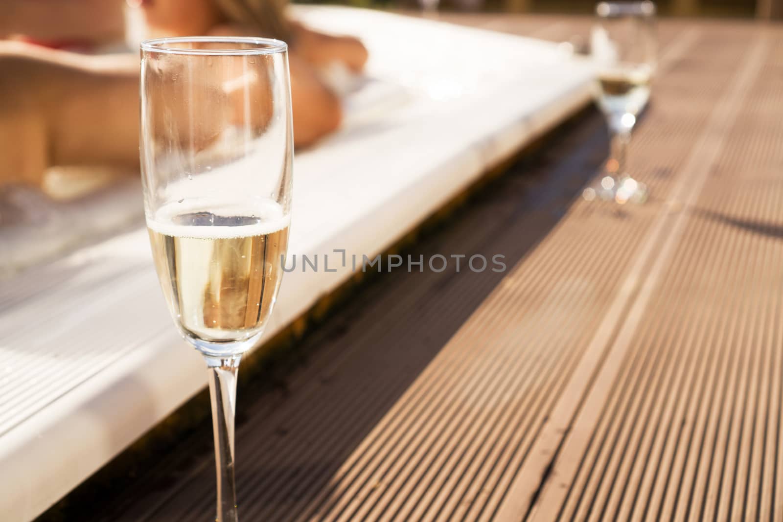 A glass of champagne by the pool on a sunny day. Blurred background for relaxation and spa concept