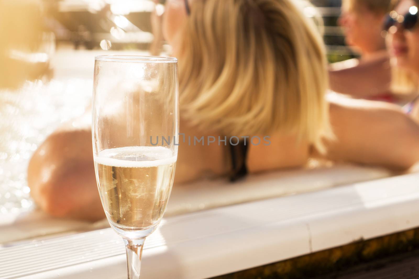 A glass of champagne by the pool on a sunny day. Blurred background for relaxation and spa concept