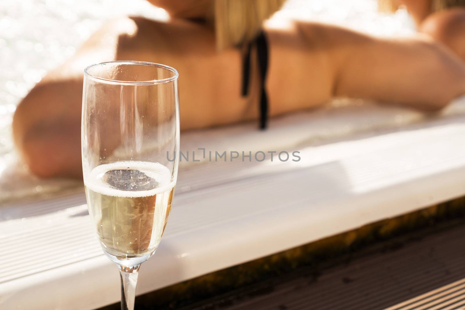 A glass of champagne by the pool on a sunny day. Blurred background for relaxation and spa concept