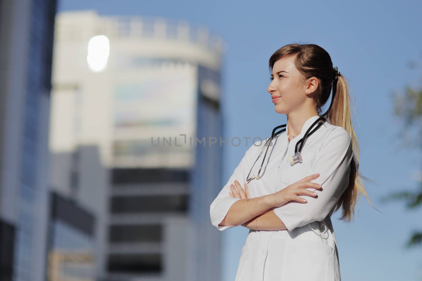 Portrait of a beautiful female doctor or nurse. Skyscraper, sky. Health concept. by selinsmo