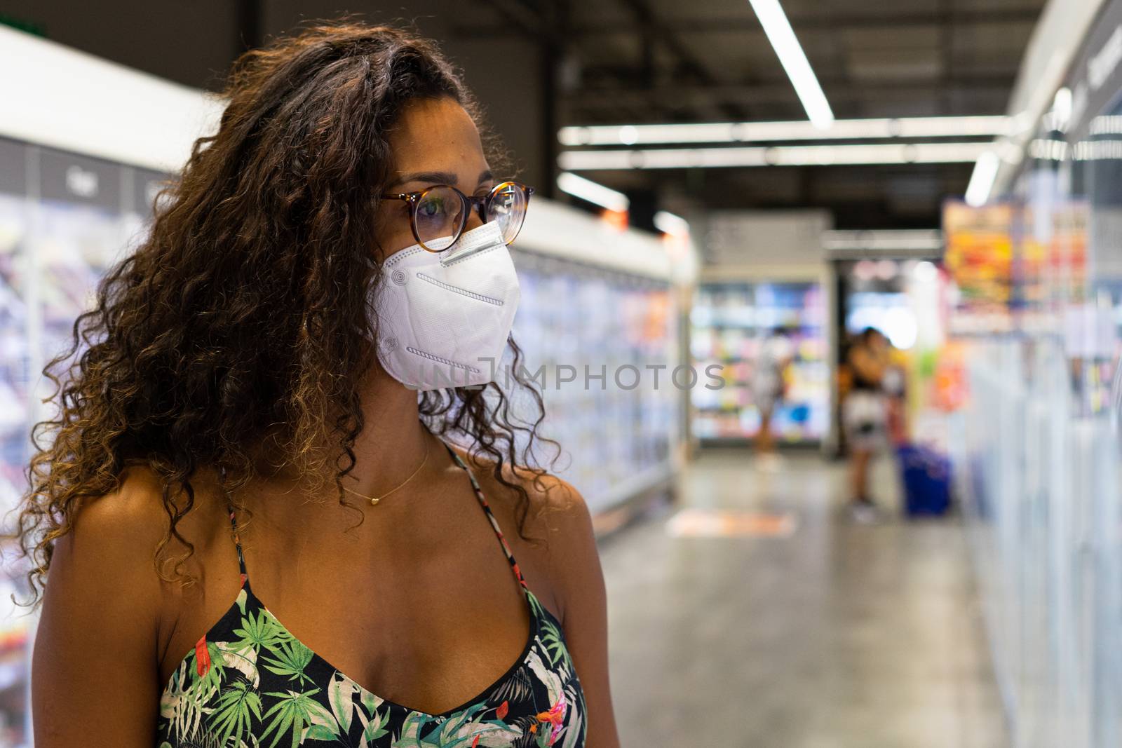 Brazilian young woman shopping in the supermarket with mask. New normality concept.