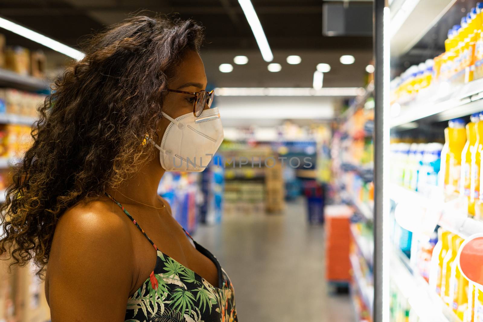 Brazilian young woman shopping in the supermarket with mask. New normality concept.