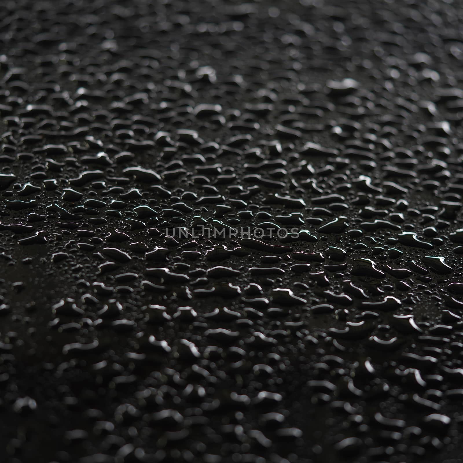 Abstract raindrops clinging to the surface of the car, black background.