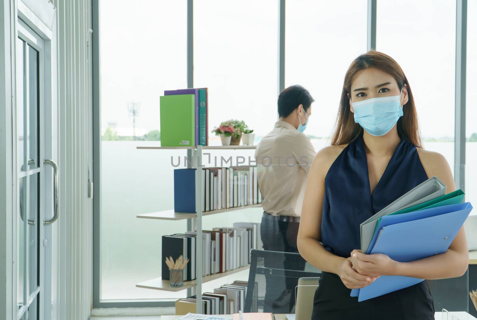 Attractive and modern Asian businesswoman. Wearing a virus protection mask while working in the office. Social distancing is a new normal. Prevent the spread of infection coronavirus or COVID-19