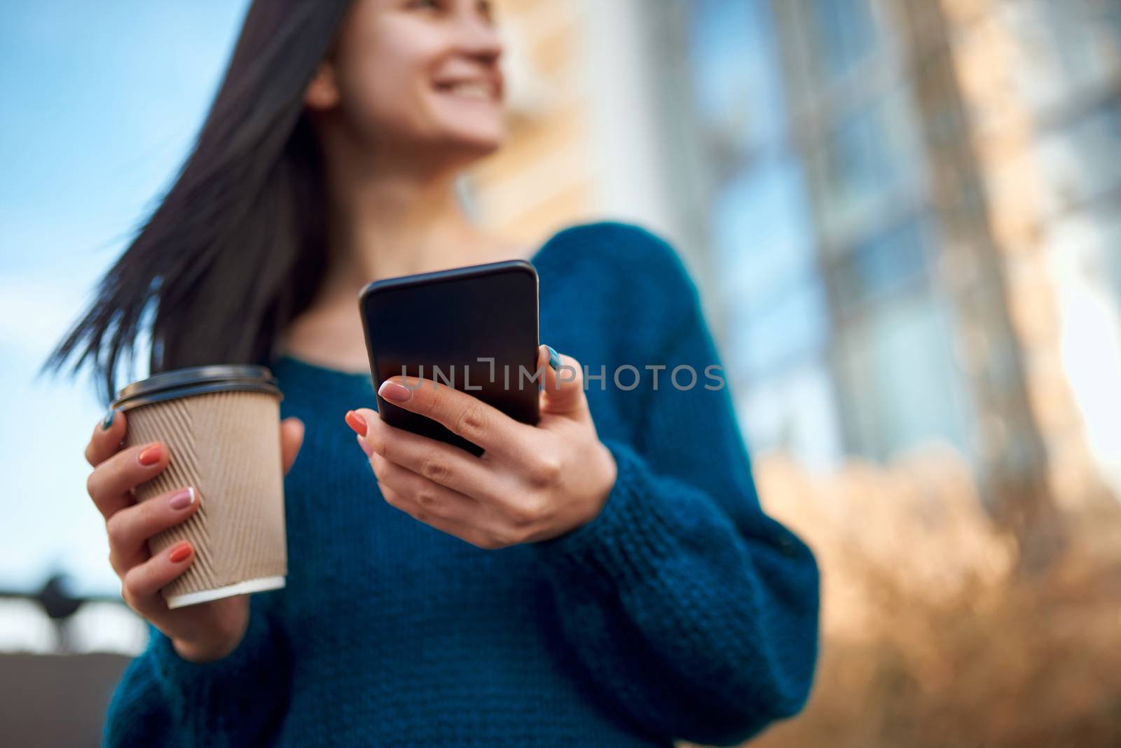 Cropped shot of cup of drink and mobile phone in woman hands by monakoartstudio