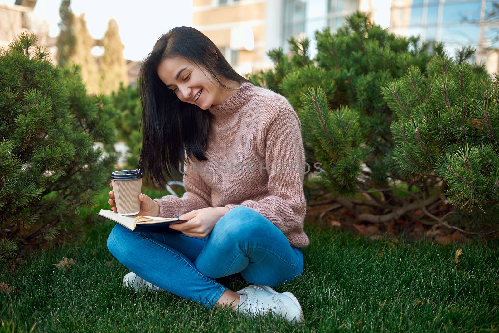 Pretty female smiling while reading interesting book outdoors by monakoartstudio