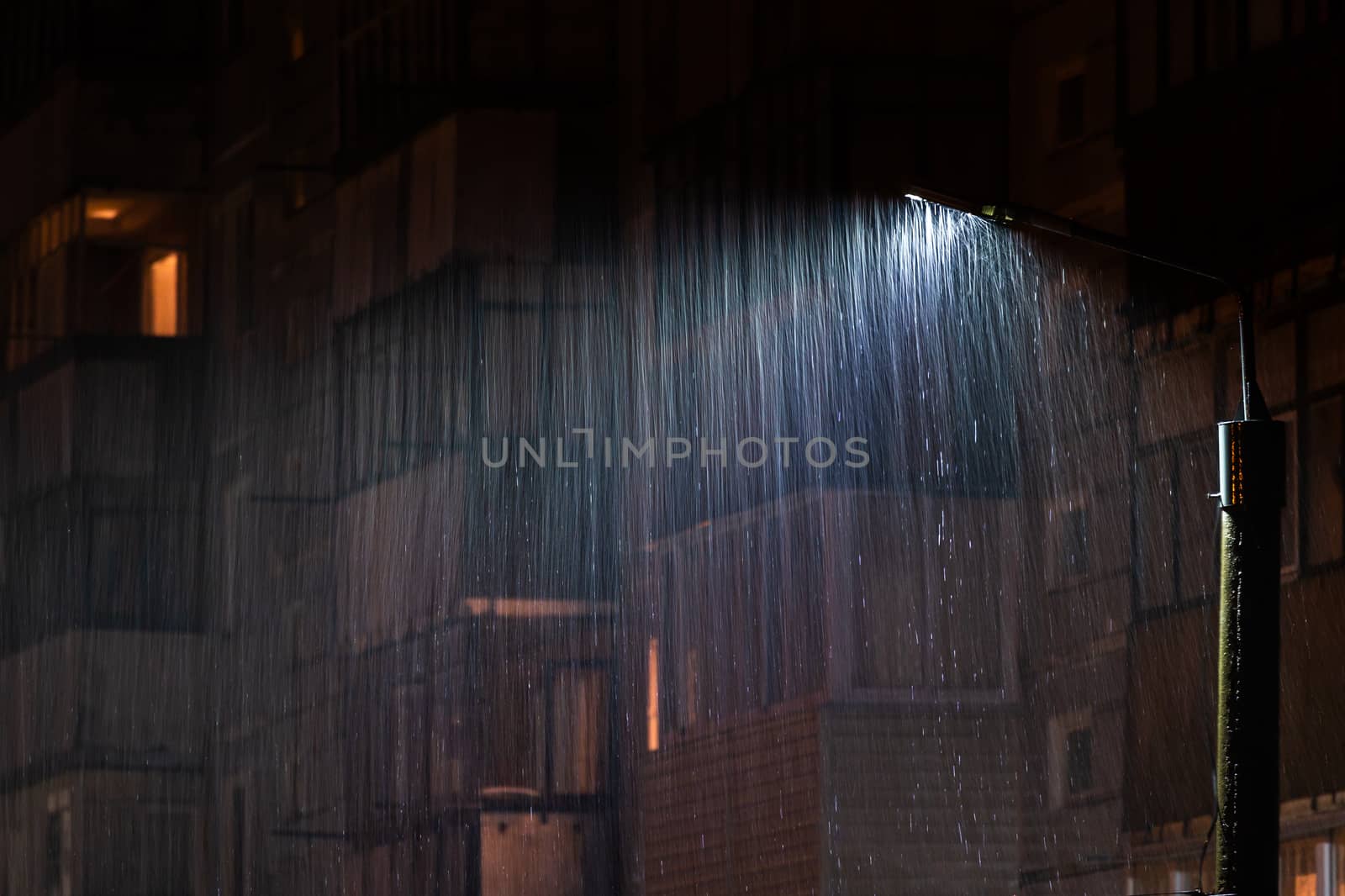 lamp post at rainy nigh with selective focus and long exposure motion blur of rain drops.