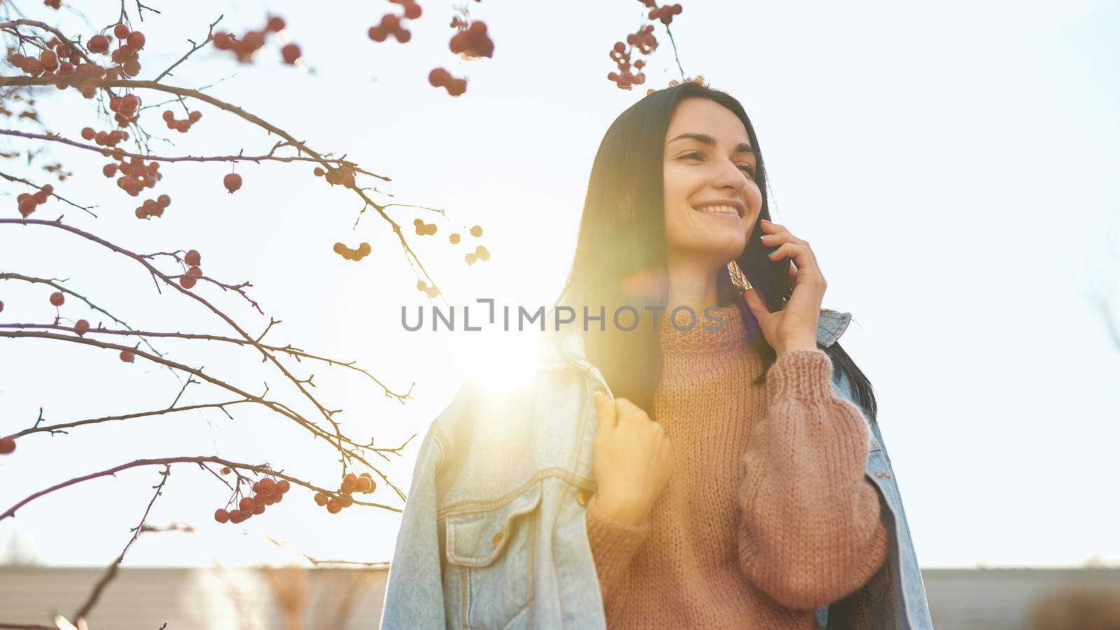 Smiling woman communicating by phone outdoors on natural backround by monakoartstudio