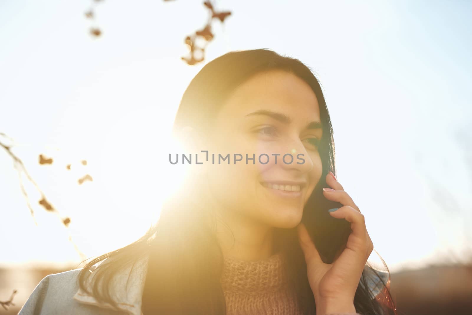 Lovely lady talking by phone in the lights of sunset by monakoartstudio