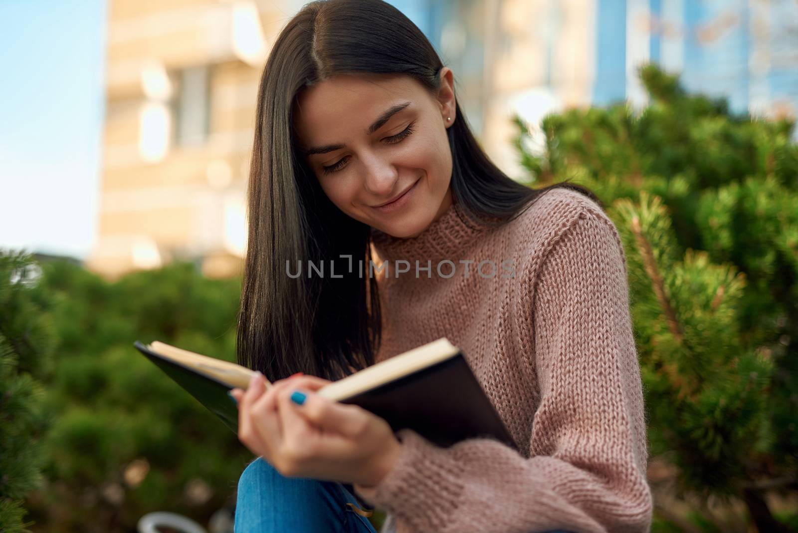 Smiling lady reading personal journal on the street by monakoartstudio