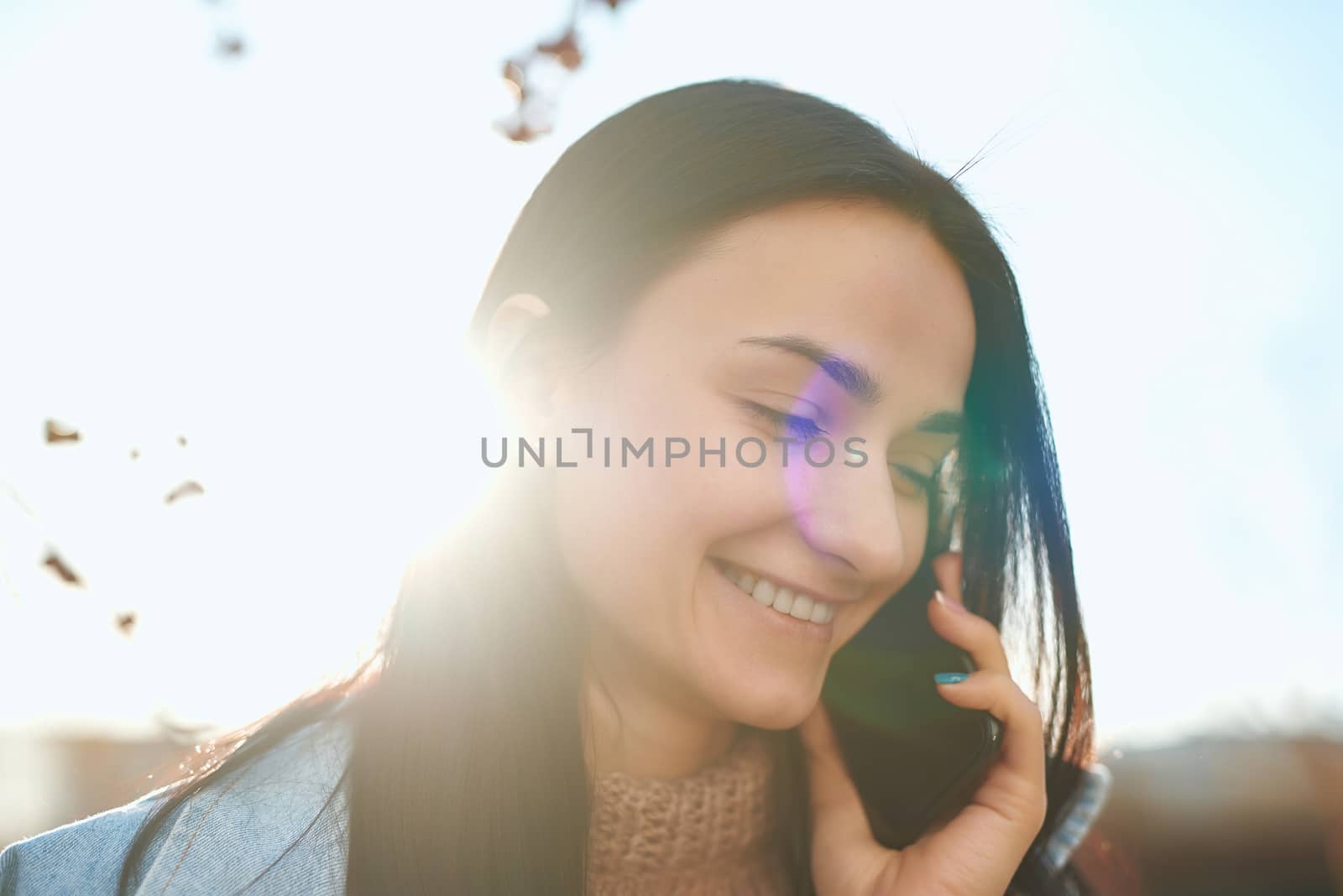Attractive female posing with a cellphone in autumn sunlight by monakoartstudio