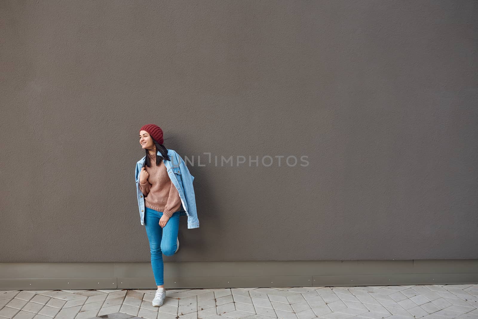 Stylish lady standing close to a dark sole-coloured wall by monakoartstudio