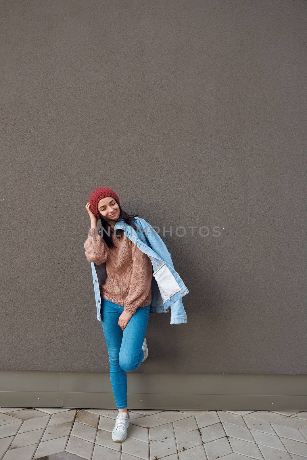 Hipster woman standing near grey fence on a city street by monakoartstudio
