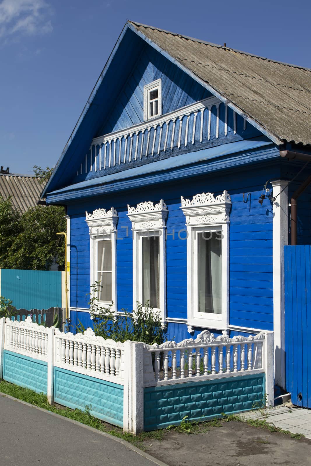 Richly decorated ornamental carved windows, frames on vintage blue wooden rural house. Countryside