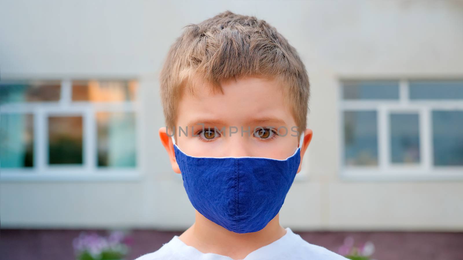 Tourist wearing mask. A caucasian boy's face wearing medical mask back to school in the city background. A boy beautiful eyes. Children eyes. Young tourist, little traveler in face mask by synel