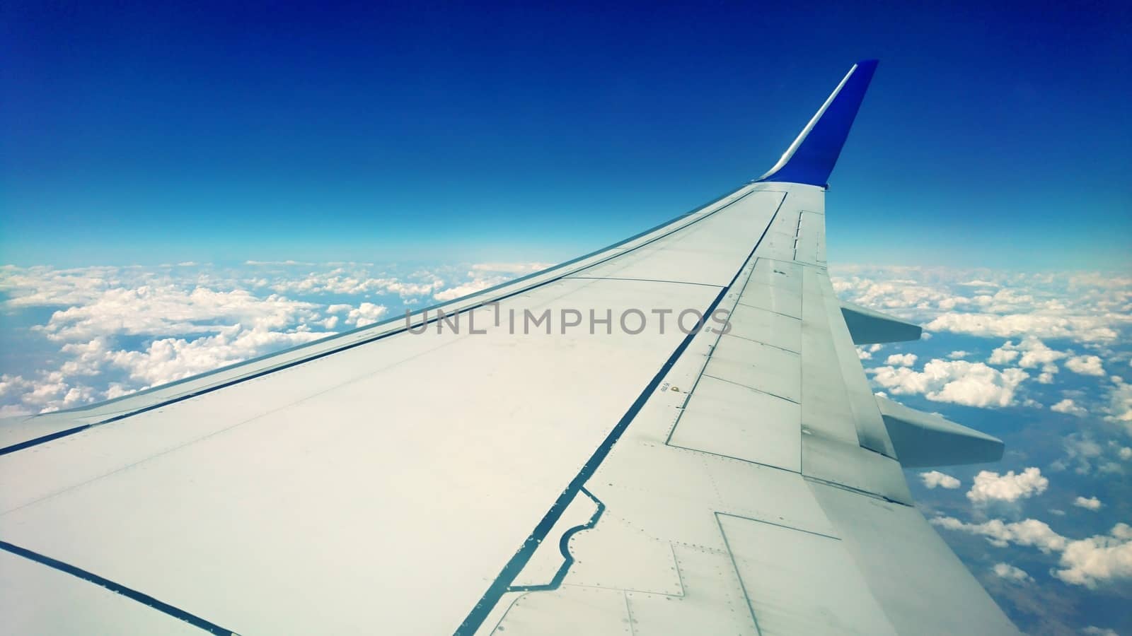 Classic passenger view of wing and sky with clouds from an airplane window during flight.