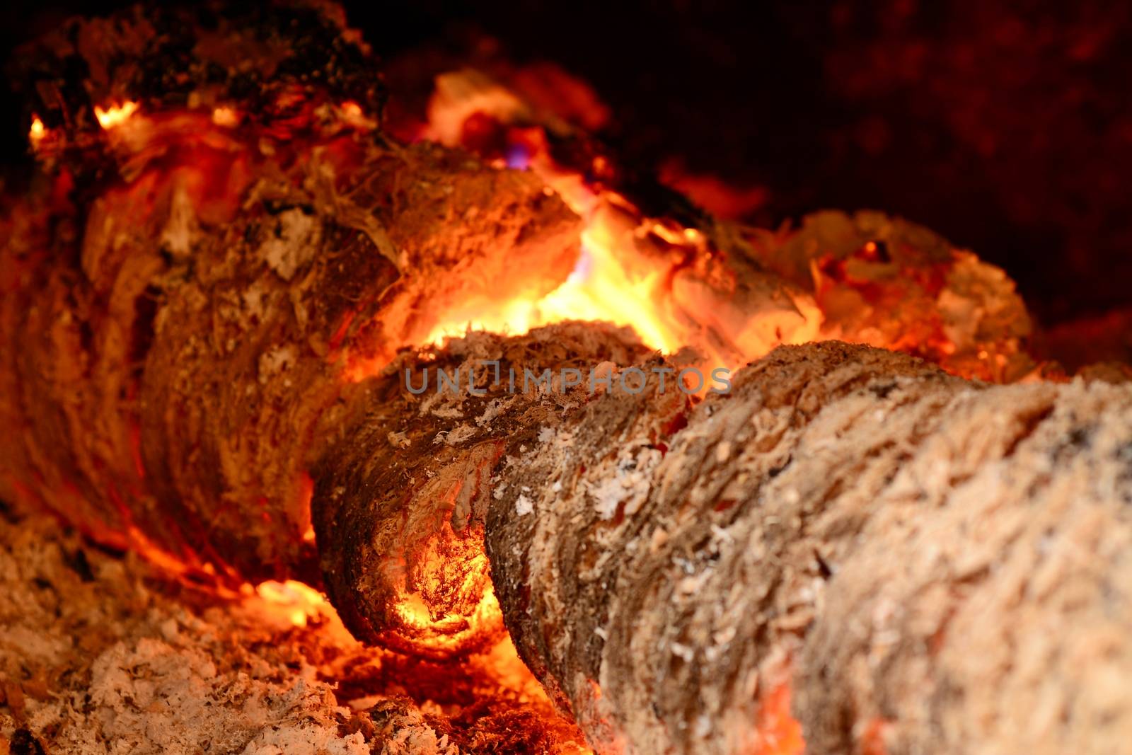 View into a fireplace with close up of a blazing burning logs.