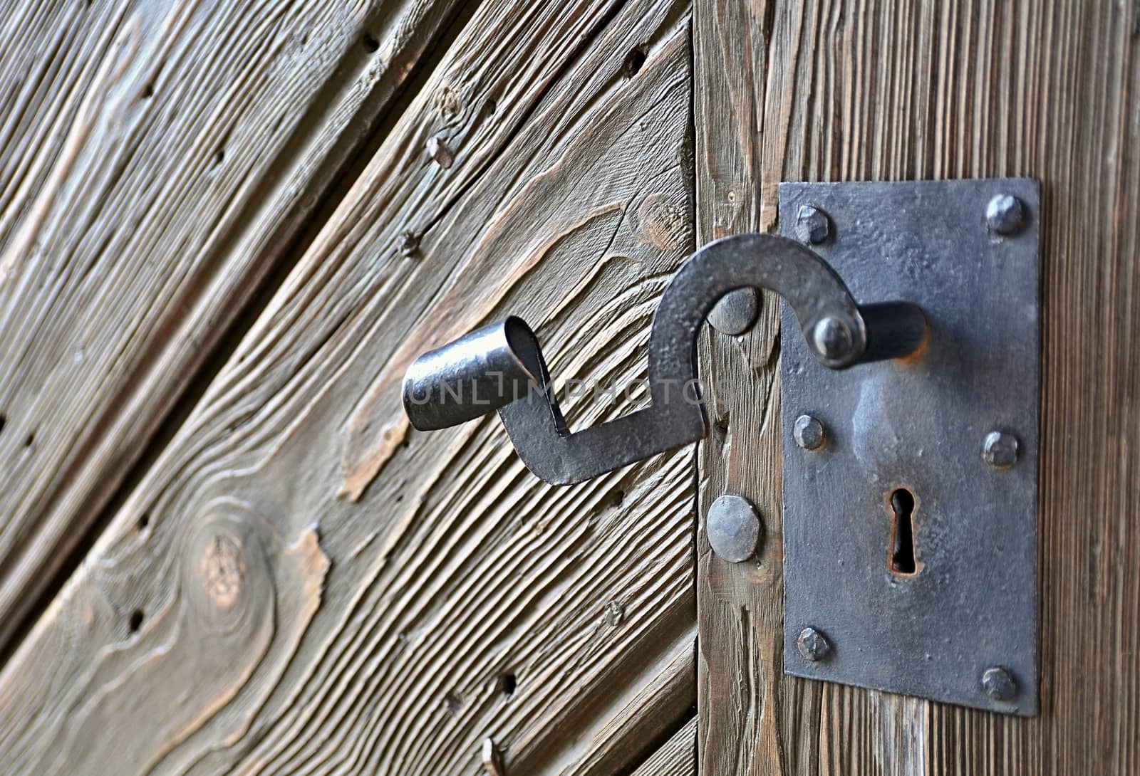 Close-up of a Vintage Rusty Door Handle on an Old Wooden Grainy Door.