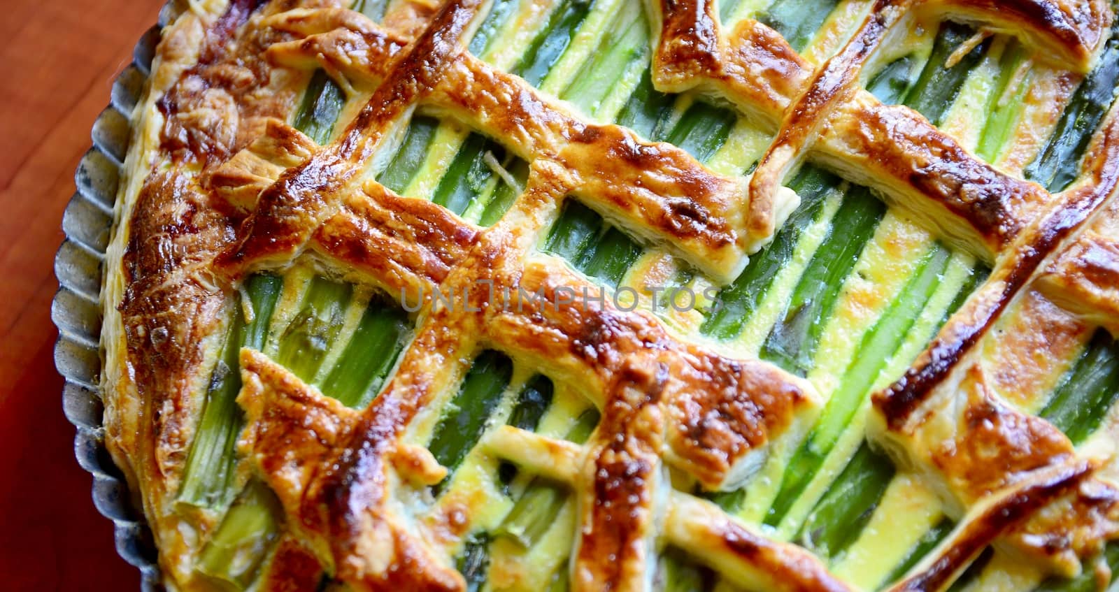 Top view of an Asparagus cake with puff pastry, cheese, ham and spinach in the one pan.