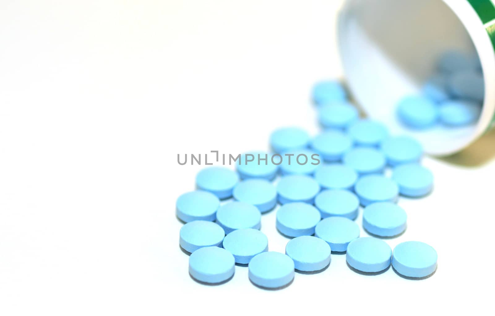 Closeup of a Blue Drug Pills Spilling Out of a Bottle on the White Background.