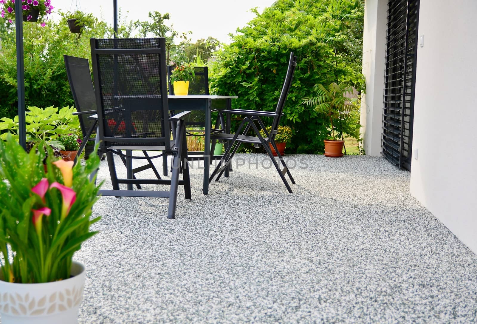 Beautiful Terrace with Decorative Natural Stone Floor, Potted Flower and Table with Chairs.