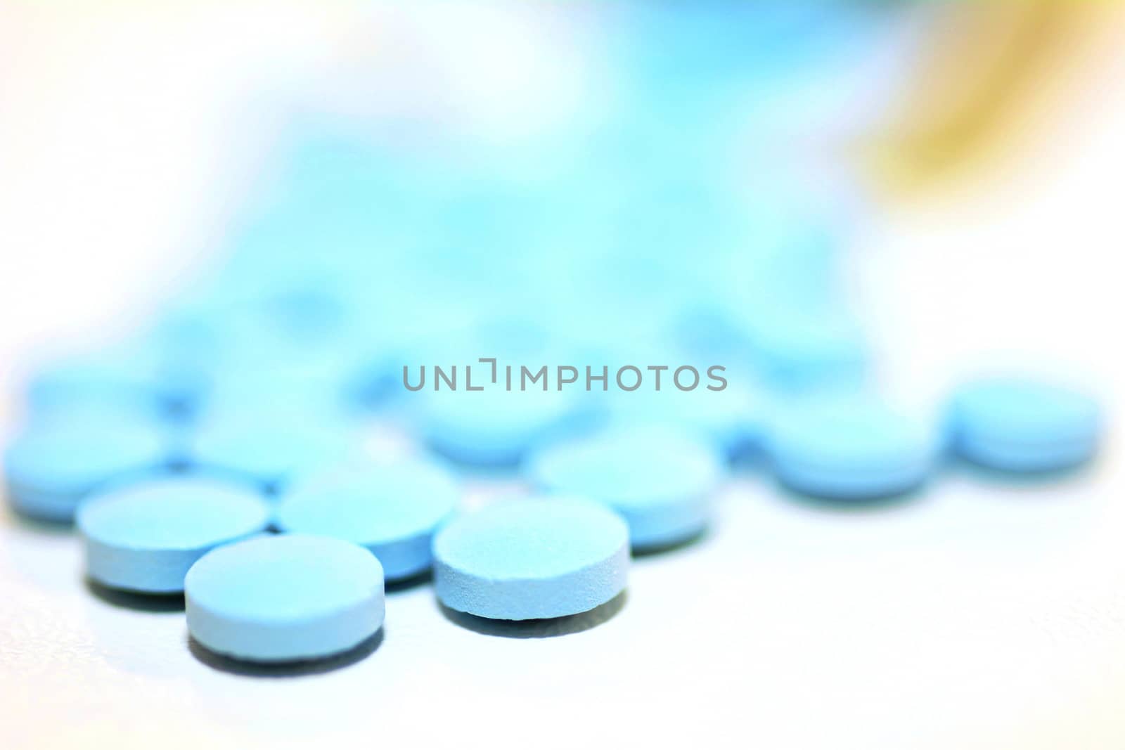 Closeup of a Blue Drug Pills Spilling Out of a Bottle on the White Background.