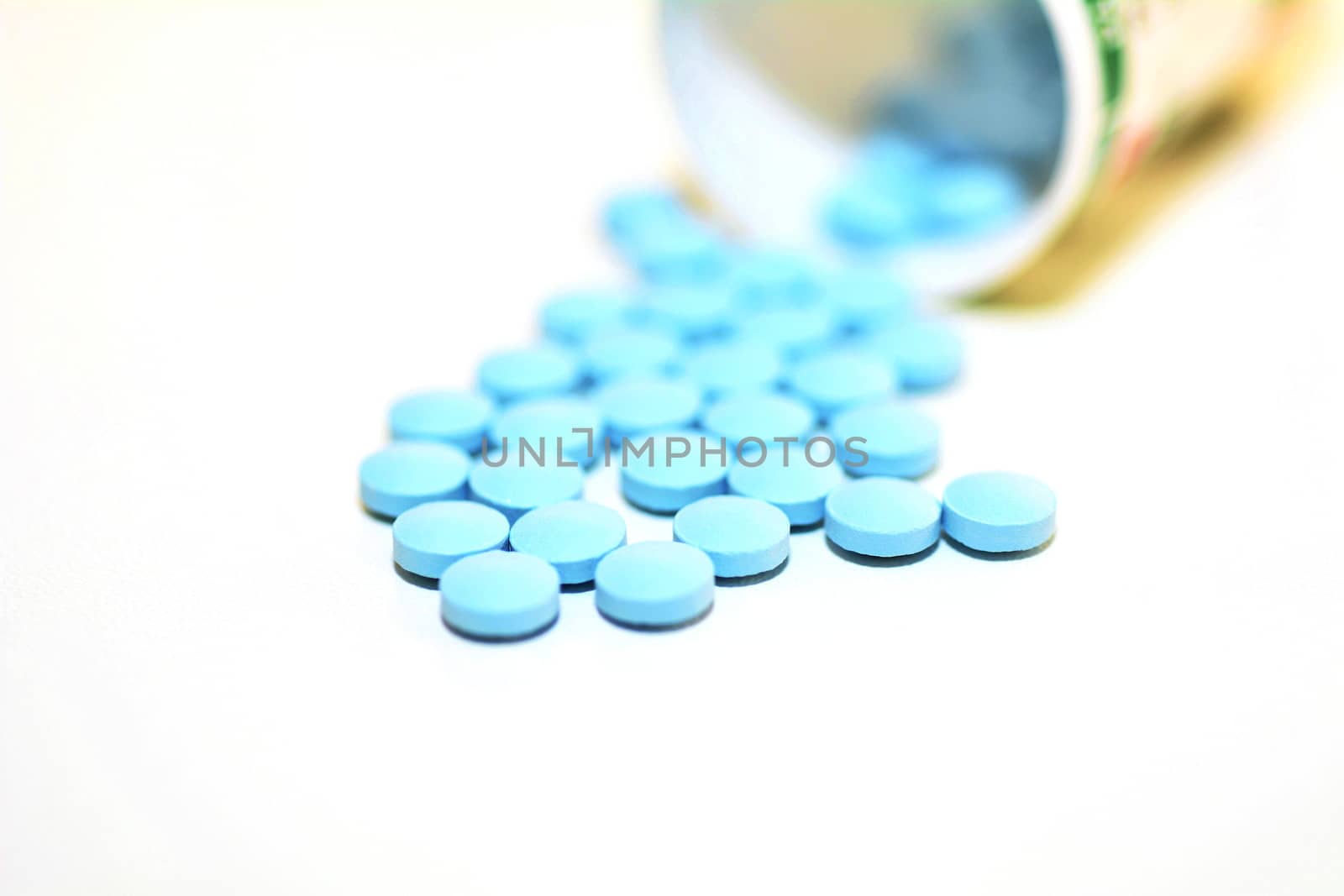 Closeup of a Blue Drug Pills Spilling Out of a Bottle on the White Background.