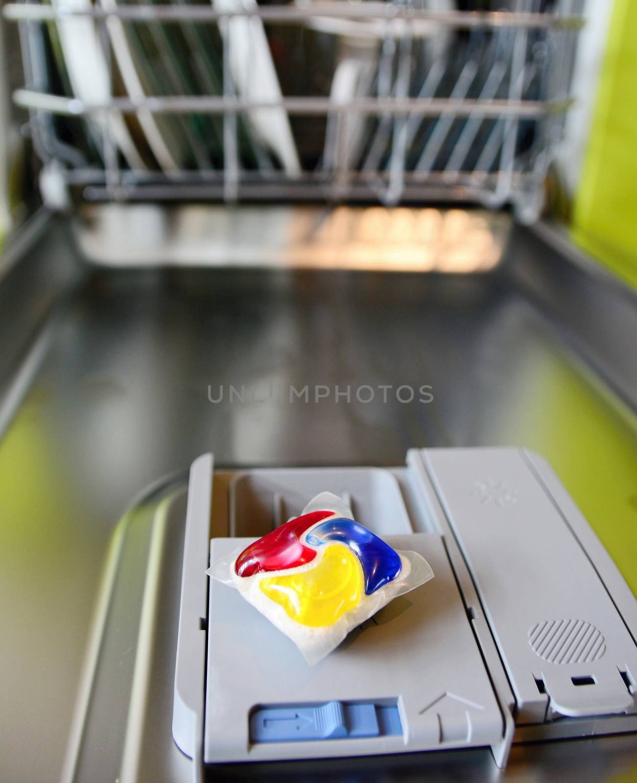 Closeup of detergent tablet put on the dishwasher tray in opened door.