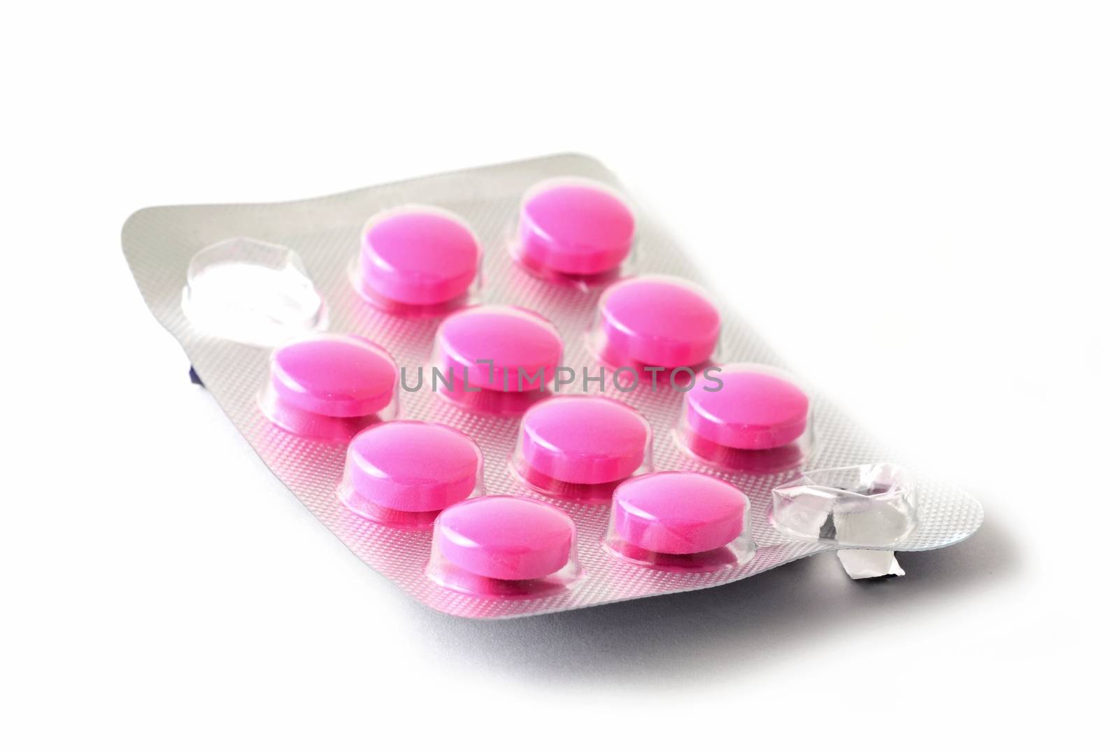 Macro shot of whole blister pack with pink pills and some squeezed missing pills over white background.