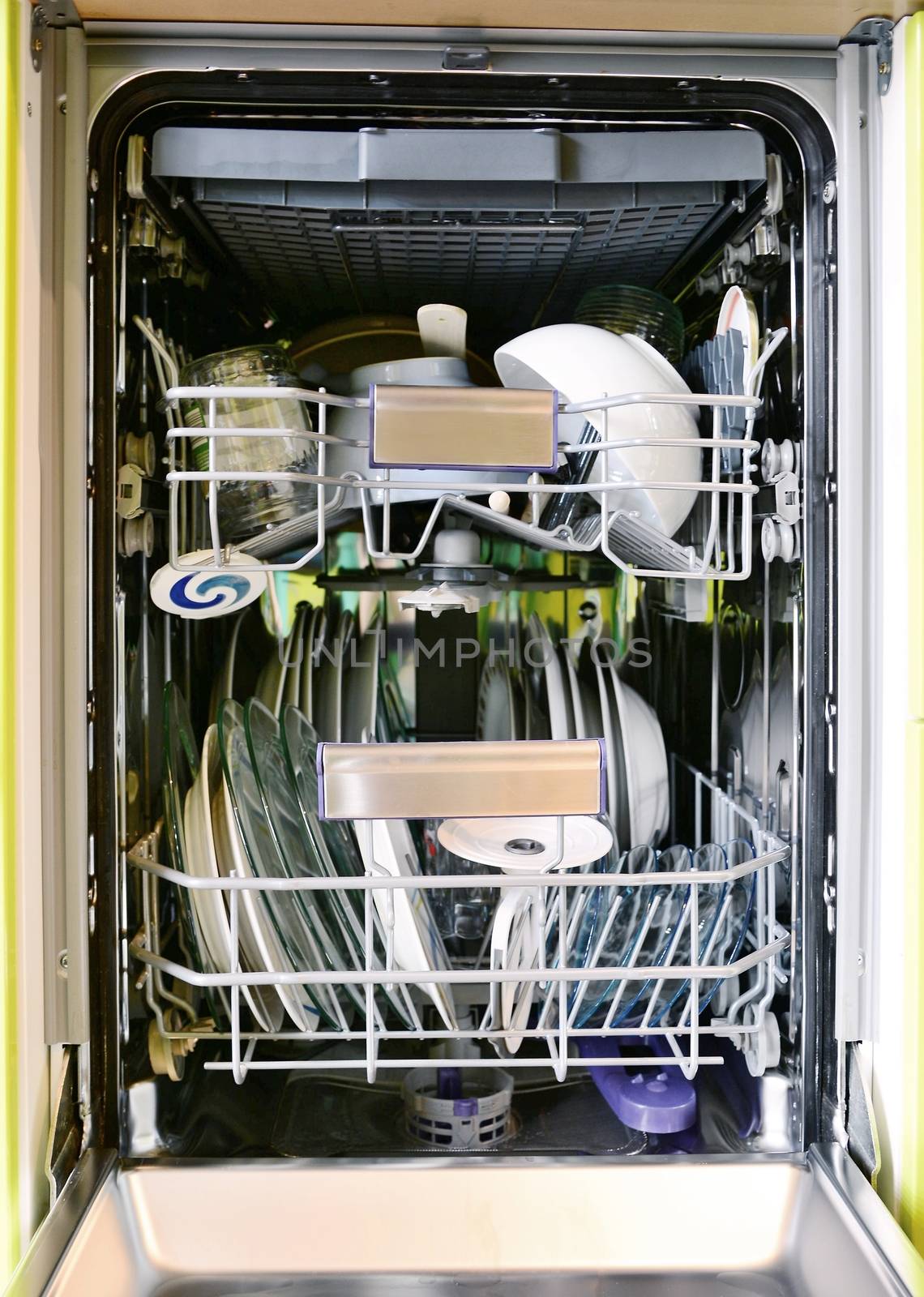 Front view into opened dishwasher full loaded of dishes. Full frame background shot.