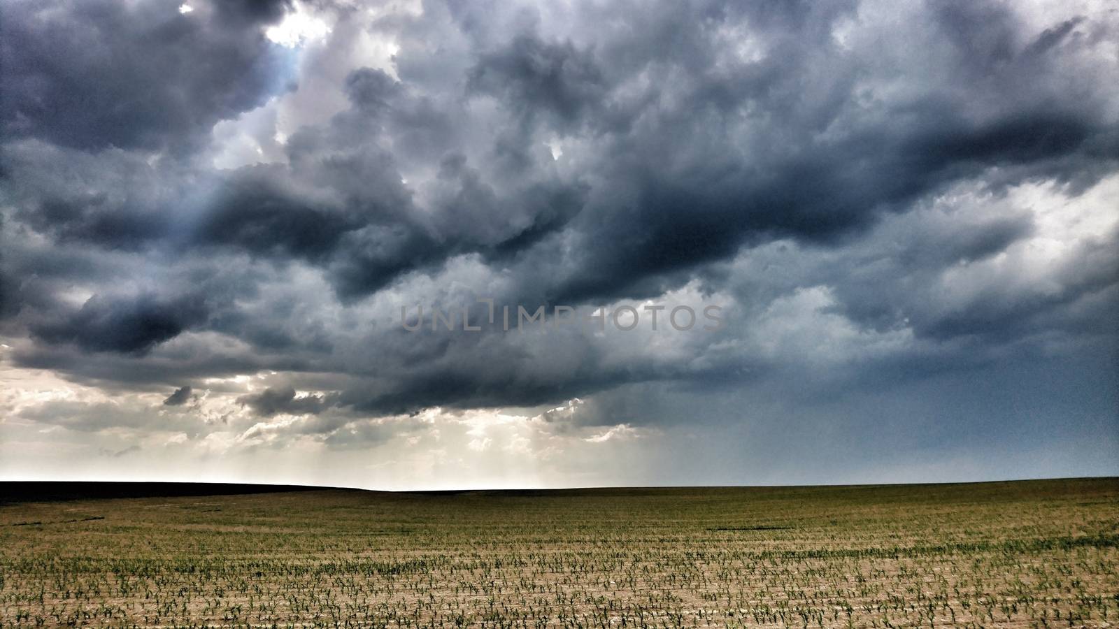 Cloudy dramatic dark sky with clouds over a field. 