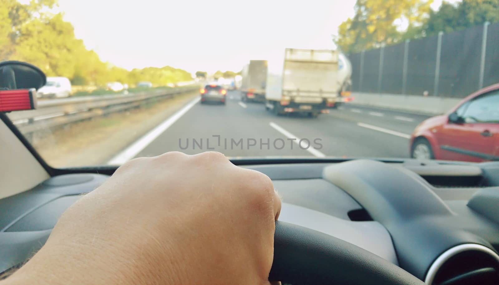 Closeup of hand holding steering wheel during driving a car on highway. POV shot, point of view first person perspective.