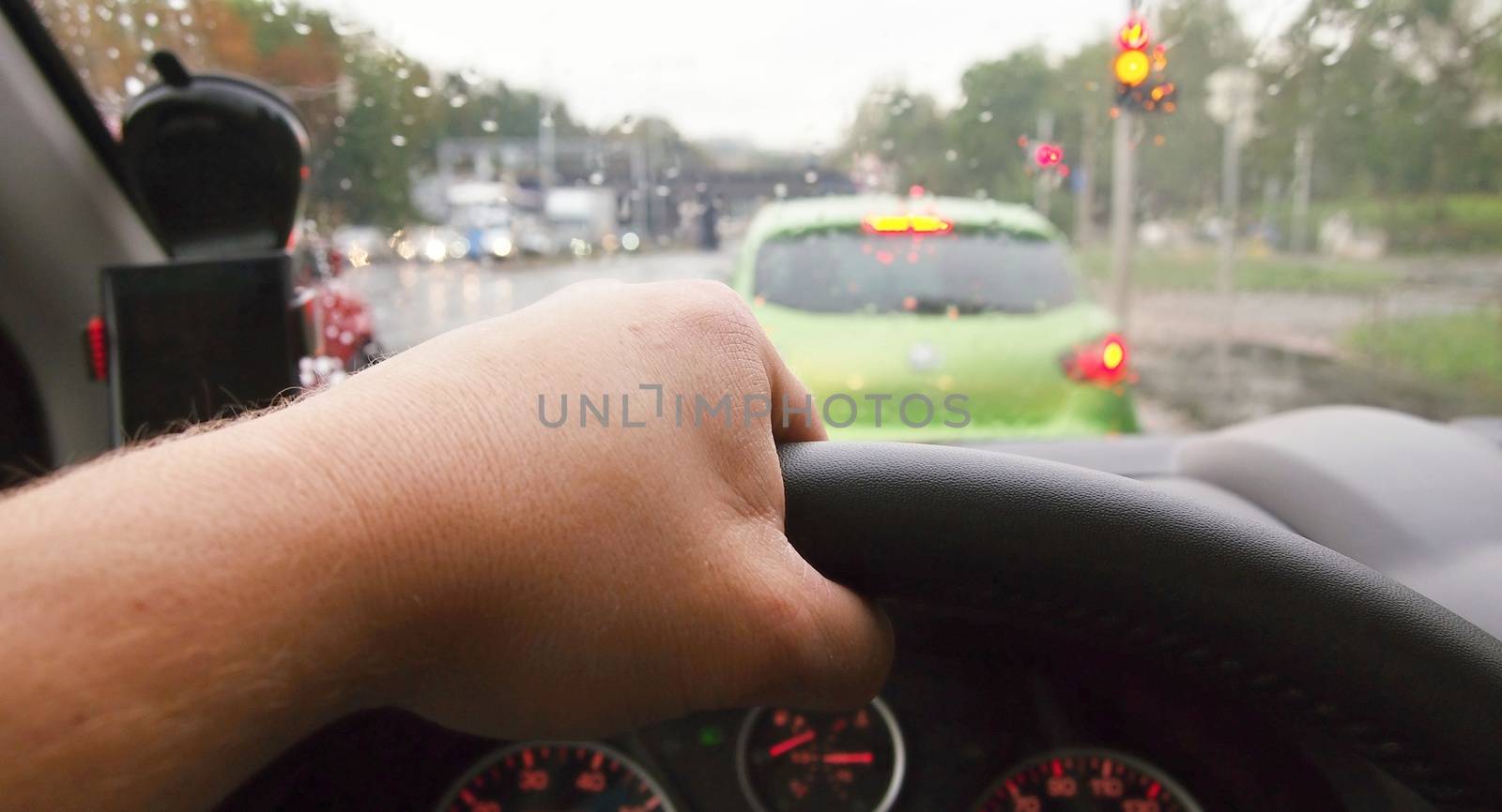 Closeup of hand holding steering wheel during driving a car in rainy weather. POV shot, point of view first person perspective.